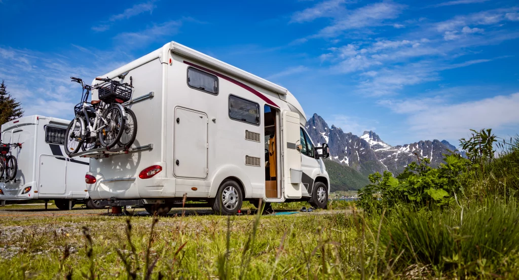 Camping-car et vélos face aux montagnes sous un ciel bleu en voyage nature
