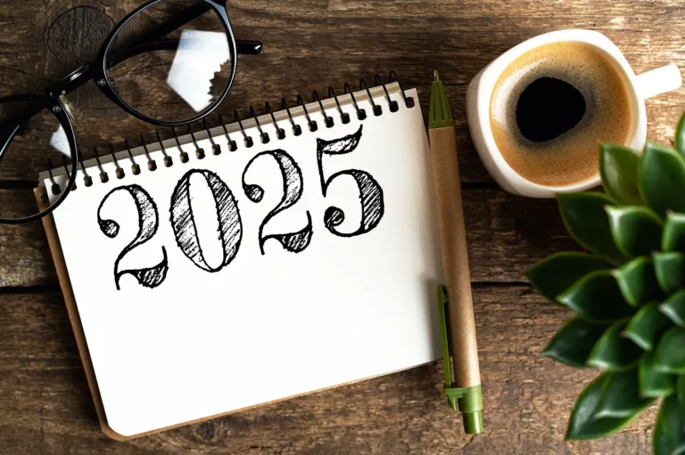 Bloc-notes avec l’inscription 2025, café, stylo et lunettes sur table