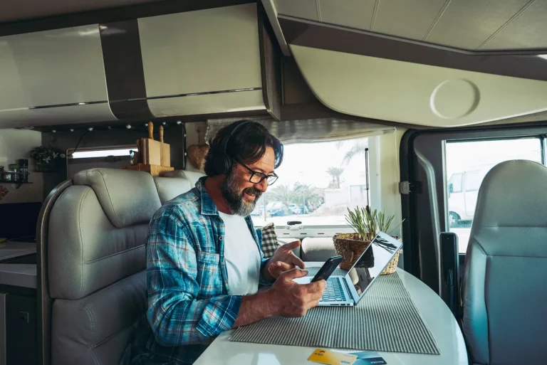 Homme en télétravail dans un camping-car avec ordi portable et casque
