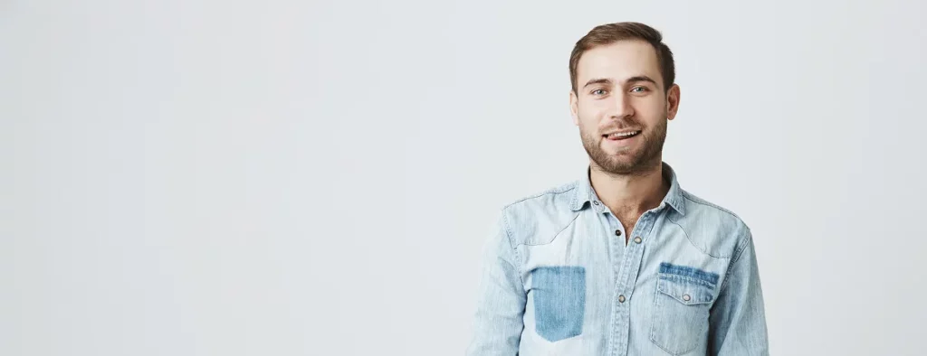 Homme souriant en chemise en jean, portrait sur fond clair